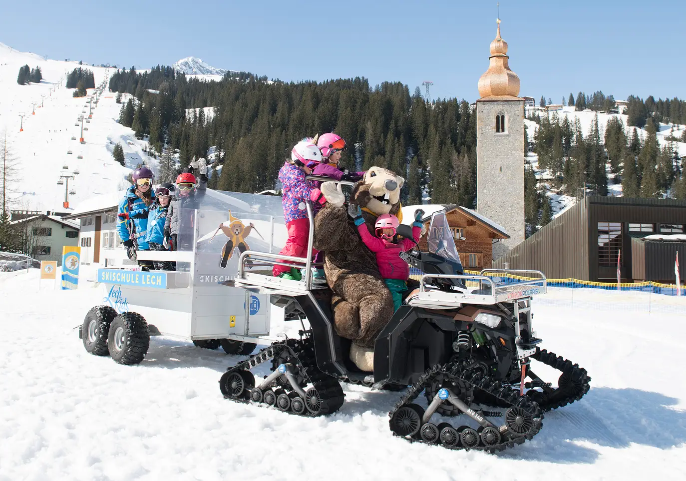 Skischule Lech Kinder mit Maskottchen auf Schneemobil